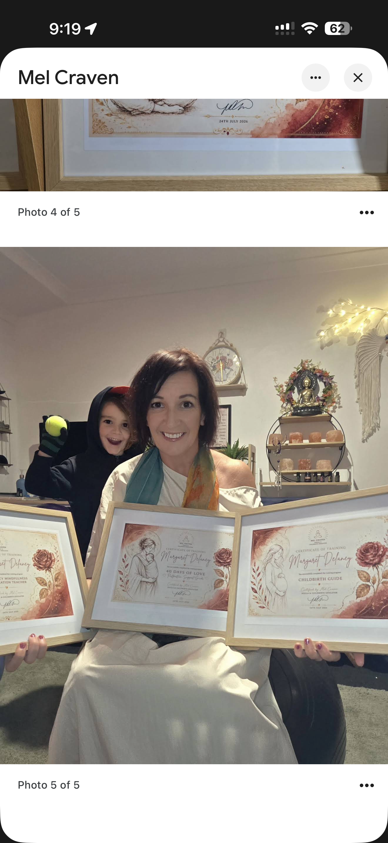 Margaret proudly holding her three framed course certificates