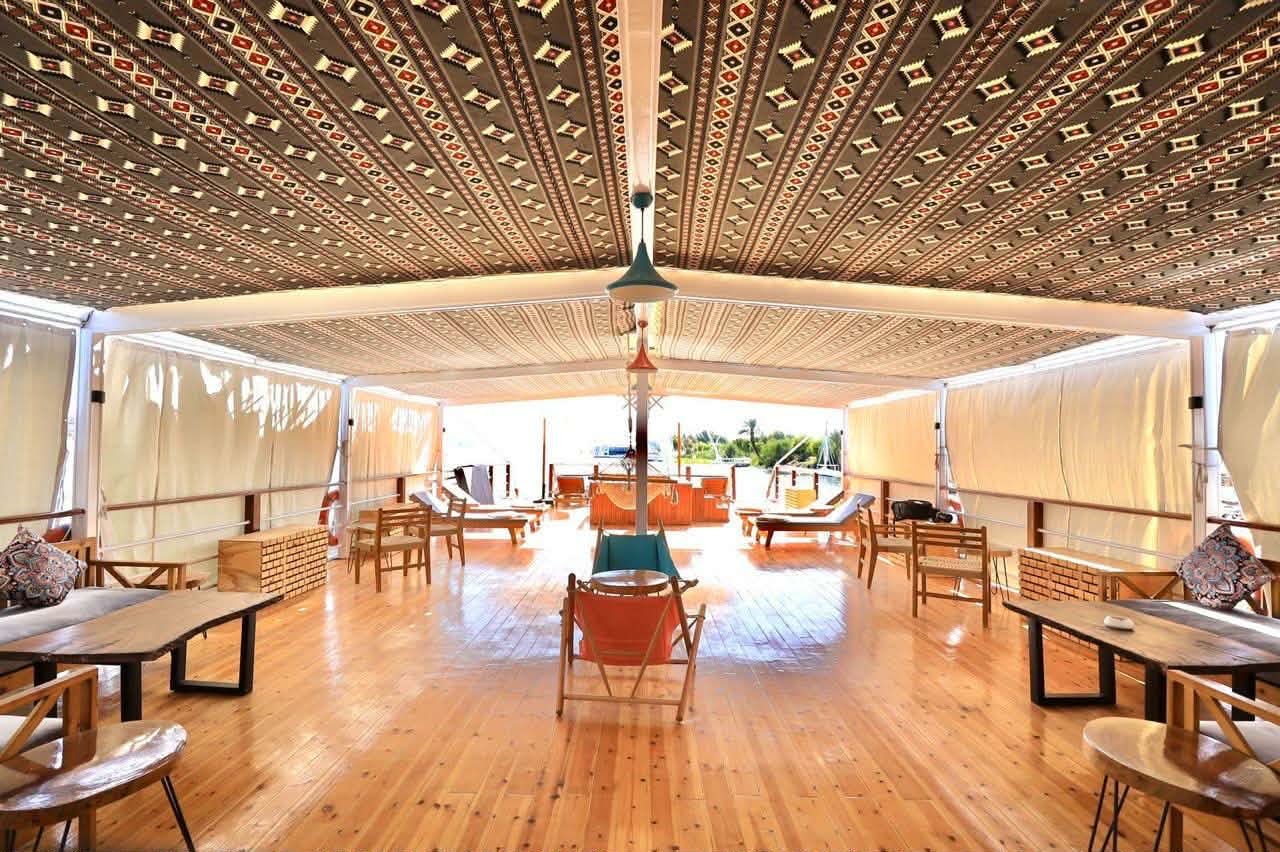 The open dahabiya lounge deck with patterned ceiling and warm timber floors