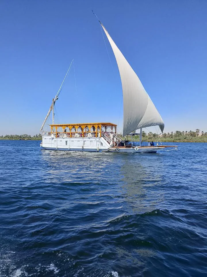 A dahabiya with white sails gliding across the Nile