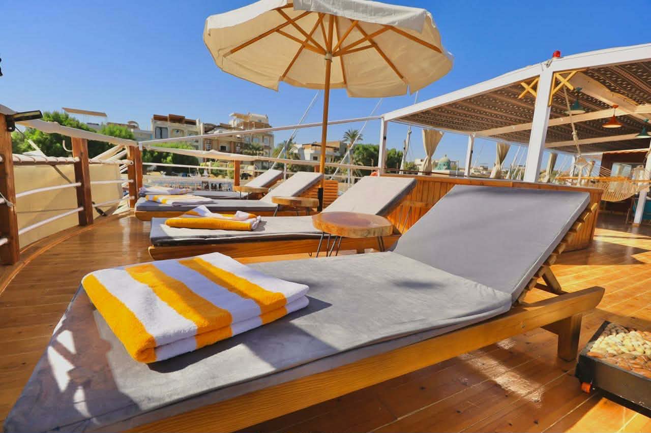 Sun lounges and umbrellas on the dahabiya deck beneath a bright blue sky